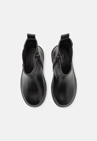 Czarne botki za kostkę wykonane z gładkiej skóry, z zamkiem błyskawicznym i dekoracyjnym wykończeniem z srebrnych koralików wzdłuż podeszwy.