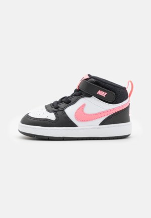 Czarno-biało-różowe wysokie buty sportowe Nike na rzep, różowe logo Nike i biała podeszwa na jednolitym tle.