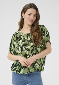 Grøn mønstret top med korte ærmer og rund halsudskæring, prydet med et bladlignende design i forskellige nuancer af grønt og sort.