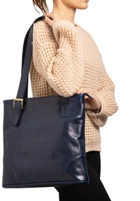 Marineblauwe leren draagtas met een gladde textuur, rechthoekige vorm, twee handvatten aan de bovenkant en een gespdetail op de band.