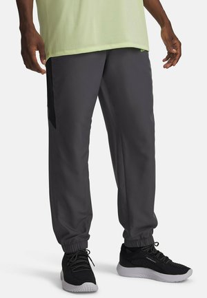 Tumedahallid spordipüksid elastsete sääreotstega, külgedel taskud ja kontrastne must paneel. Kandmisel mustad spordijalatsid.