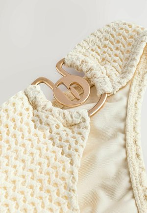 Woven cream bikini top with a textured crochet pattern, featuring a gold hardware clasp detail and smooth interior fabric.