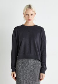 Mørk grå kort sweatshirt med rund halslinning, prydet med små svarte detaljer, sammen med et teksturert grått strikkeskjørt.