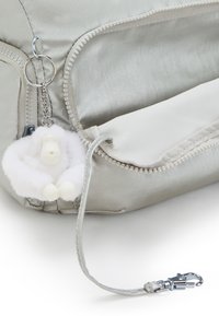 Silver nylon bag featuring a zip closure, side pocket, and a white fluffy keychain attachment with a small figure and claw accents.