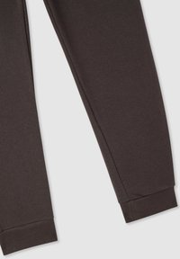 Pantaloni della tuta marroni scuri realizzati in morbido tessuto, con un taglio affusolato e polsini a costine alle caviglie. Nessuna tasca visibile o motivi.