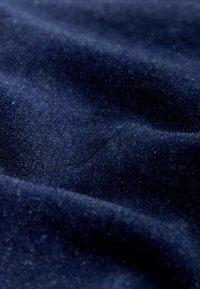 Tela azul oscuro suave con una textura lisa, ligeramente aterciopelada, y pliegues suaves que crean sombras sutiles.