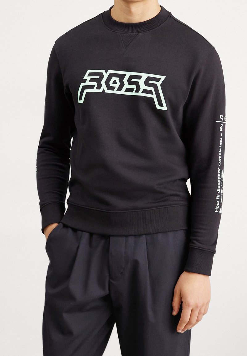 Sweat-shirt noir avec un motif graphique bleu clair sur le devant et un texte blanc détaillé sur la manche droite. Matière en mélange de coton.