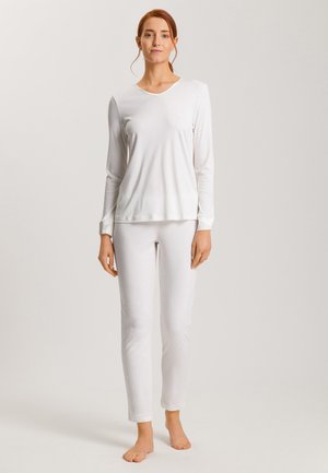 Top bianco a maniche lunghe e pantaloni abbinati in tessuto morbido. Il top presenta un collo a V; i pantaloni sono aderenti con una texture liscia.