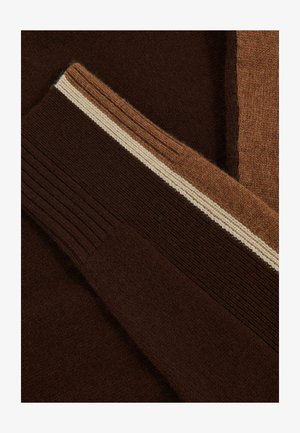 Tissu de pull marron avec une texture côtelée. Présente des rayures contrastantes de marron clair et de crème le long des poignets et du col.