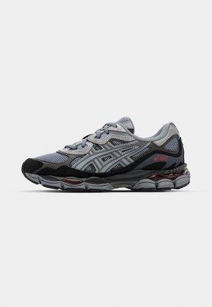 Graue und schwarze Sportschuhe mit einem Mesh-Obermaterial, reflektierenden Akzenten und einer gepolsterten Sohle, die ein markantes rotes Detail aufweist.