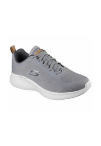 Zapatilla deportiva gris con parte superior de malla transpirable, suela blanca acolchada y acentos texturizados. Cuenta con cordones y una lengüeta en el talón.