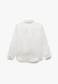 Camisa de lino blanca con mangas largas, un collar, un pliegue en la espalda y puños abotonados. Textura suave con un ajuste relajado.