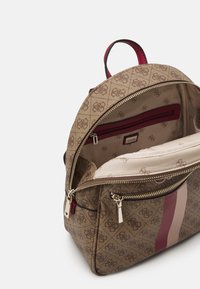 Mochila marrón con un patrón y acentos a rayas, que cuenta con un compartimento principal con cremallera, bolsillo interior y forro rojo. Con herrajes de cremallera dorada.