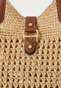 Πλεγμένη τσάντα από ψάθα σε ανοιχτό μπεζ χρώμα, με καφέ δερμάτινη λουρί και πασπαλισμένο γκολντ κουμπί. Υφασμάτινη επιφάνεια με ανοιχτό πλέγμα.