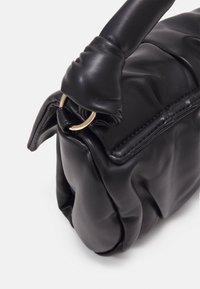 Mustapasta nahkalaukku, jossa on pehmeä, tikattu muotoilu. Ominaisuuksiin kuuluu pyöreä muoto ja solmittu kahva, jossa on kultainen metallirengas.