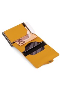 Żółty skórzany portfel z zapięciem na zatrzask, posiadający przegrodę na banknoty oraz slots na karty kredytowe, wyróżniający się kontrastowym szwem.