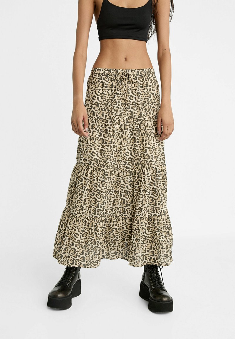 Leopardenprint-Tiermaxikleid in Beige und Braun, mit elastischem Taillenbund und Rüschendetails, kombiniert mit schwarzen Plateau-Stiefeln.