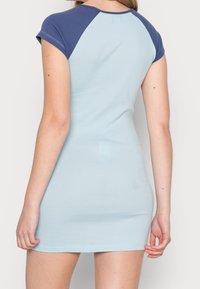 Světle modré šaty s krátkými rukávy a námořnickými akcenty na ramenech. Měkký, elastický materiál. Přiléhavý střih, délka po kolena a hladká textura.