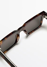 Schildpatt-Sonnenbrille mit rechteckigem Rahmen, dunklen Gläsern und silbernen Hardware-Akzenten an den Scharnieren. Glatte, glänzende Oberfläche.