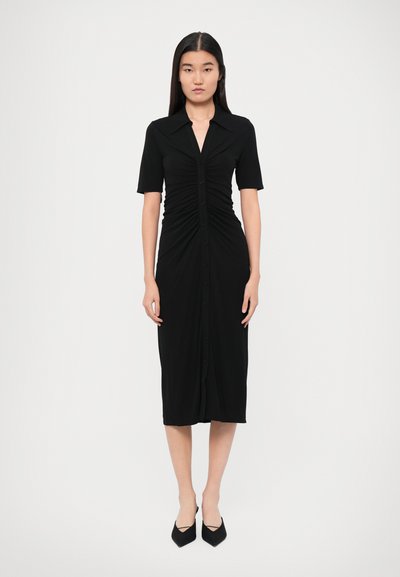 Crna uska haljina s kratkim rukavima, kopčanjem na gumbe sprijeda, naboranom teksturom u struku i duljinom do sredine lista.