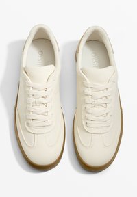 Weiße Leinenschuhe mit glatter Textur, runder Zehenpartie und Schnürdesign. Die Gummisohle hat einen braunen Akzent. Leicht und atmungsaktiv.