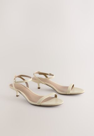Beige Sandalen mit offenem Zehenbereich, strukturiertem Obermaterial, dünnem Knöchelriemen und Kitten-Heel. Verfügen über eine glatte Innensohle und ein minimalistisches Design.