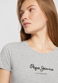 T-shirt grigia in cotone a maniche corte, con colletto tondo e logo nero "Pepe Jeans London" stampato sul davanti.
