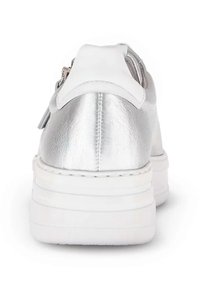 Sneakers metallici argento con tallone bianco, caratterizzati da una suola spessa bianca e un dettaglio con zip. Il materiale appare liscio con una finitura lucida.