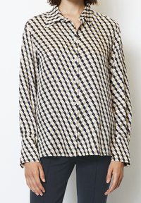 Camicia a maniche lunghe con bottoni di colore crema e navy con un motivo geometrico. Tessuto morbido, colletto classico e orlo dritto.