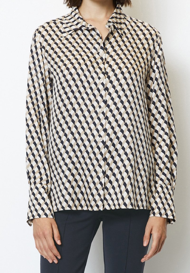 Camicia a maniche lunghe con bottoni di colore crema e navy con un motivo geometrico. Tessuto morbido, colletto classico e orlo dritto.