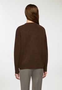 Brązowy sweter dzianinowy o luźnym kroju, okrągłym dekolcie i długich rękawach. Miękka faktura, z prostym, eleganckim wzorem.