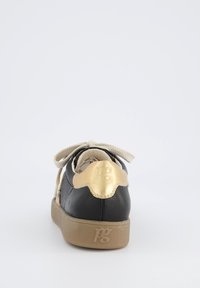 Czarne skórzane trampki z metaliczno-złotym akcentem na pięcie, beżową teksturowaną podeszwą i beżowymi sznurówkami. Gładka powierzchnia z minimalnym wzorem.