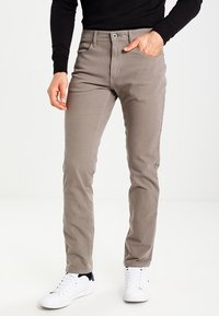 Lichtgrijze katoen chino's met een recht gesneden pasvorm, vijf zakken, knoopsluiting en subtiele textuur, in combinatie met witte sneakers.