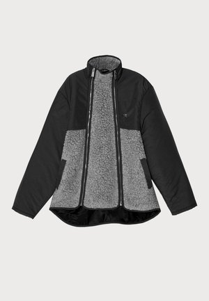 Veste noire et grise avec un corps en polaire et un extérieur lisse. Elle comporte un col haut, une fermeture éclair et des poches latérales.