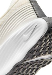Close-up of the sole and heel of a white and gray Nike sneaker showing textured tread and the embossed Nike swoosh logo.