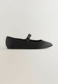 Ballerine noire avec un bout pointu, fabriquée en matériau lisse. Elle possède une lanière avec un accent en métal circulaire au niveau de la cheville.