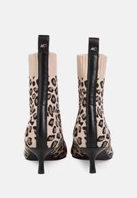 Strick-Leopardenmuster-Ankle Boots mit schwarzen Lederakzenten, schlanken Absätzen und gerippten Bündchen, ausgestattet mit einer abgerundeten Spitze und strukturierten Oberflächen.