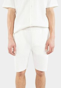 Vit, ribbad t-shirt med kort ärm och matchande shorts i en avslappnad passform. Knäppning och subtil textur. Slät tygfinish.