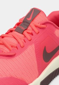 Ναike αθλητικό παπούτσι τρεξίματος σε φωτεινό ροζ δίχτυ με υφασμάτινες λεπτομέρειες. Διαθέτει φωτεινά κορδόνια, ετικέτα "Just Do It" και αντίθετη λεπτομέρεια λογότυπου.