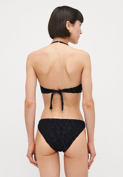 Black bikini set featuring a textured fabric with a repeated logo pattern, adjustable ties at the back of the bandeau top and low-rise bottom.