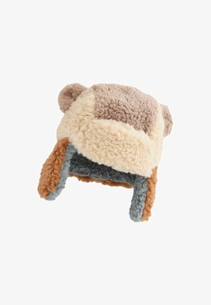 Umelohladový klobúk v krémovej, hnedej a sivej farbe s plyšovou textúrou. Má ušné klapky a zaoblený vrch zdobený malými ušami.