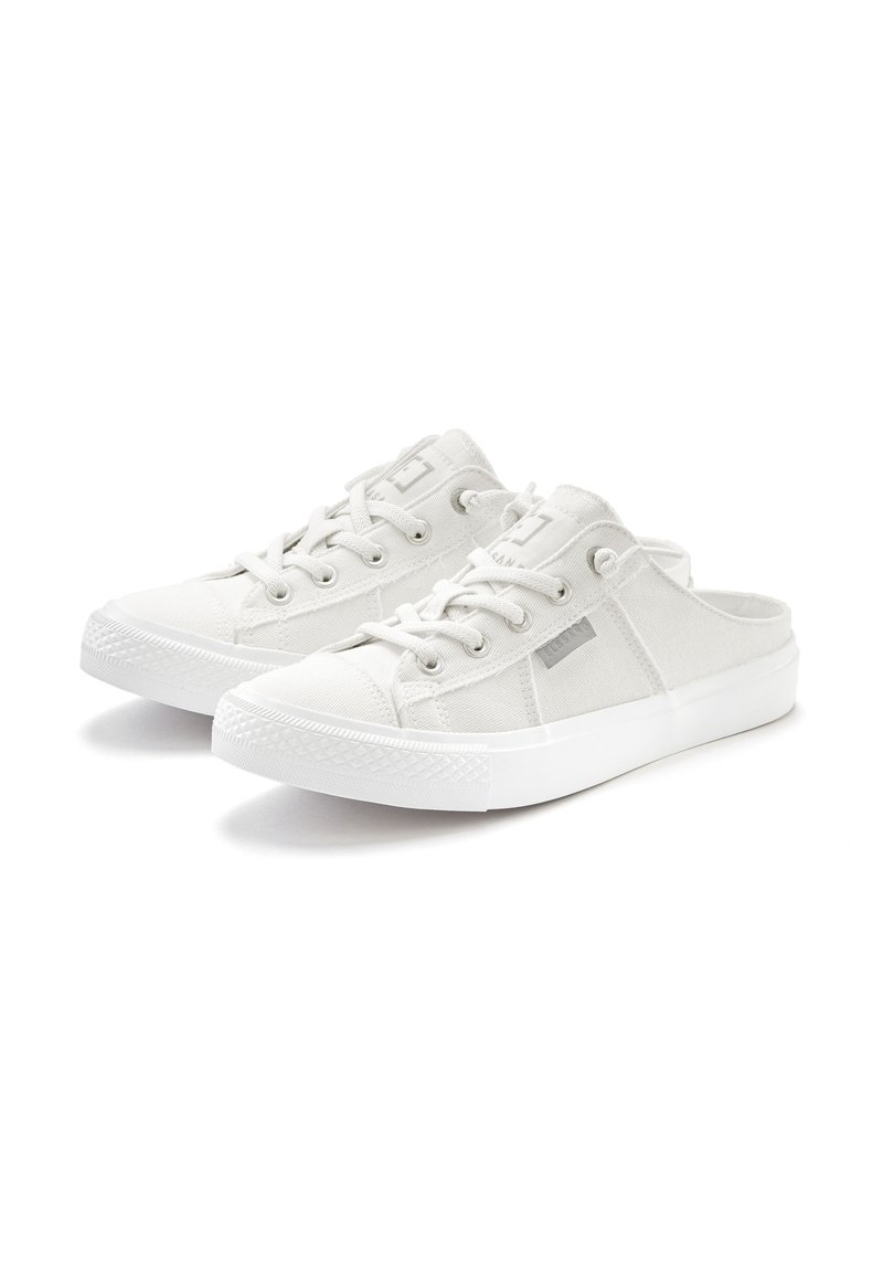 White canvas slip-on shoes with a textured surface, featuring lace-up detailing, round rubber toe cap, and flat white sole.