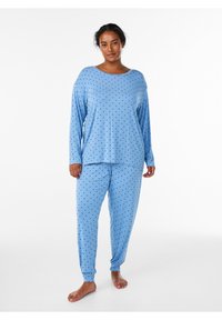 Blå pyjamaset består av en långärmad tröja och matchande byxor, båda med prickigt mönster. Tillverkade av mjukt material, löst sittande med elastiska muddar.