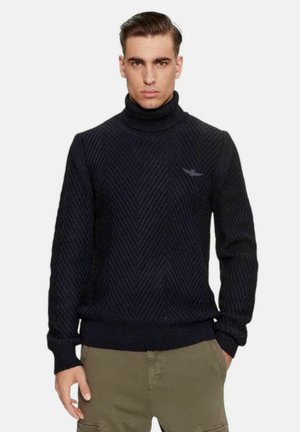 Maglione a collo alto lavorato a maglia in un blu navy scuro con motivo a zig-zag, maniche con polsini a costine e orlo, caratterizzato da un logo discreto sul lato sinistro del petto.