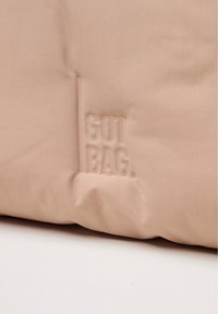 Borsa in tessuto rosa con texture liscia, caratterizzata da un logo in rilievo "GOT BAG" su un lato. Design minimalista con bordi morbidi.