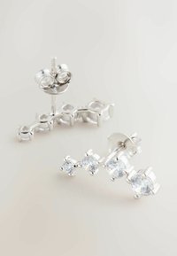 Strieborné náušnice na štuple s oblúkovým dizajnom a štyrmi čírymi, okrúhlymi kameňmi z kubickej zirkónie, každý zasadený v elegantnom lesklom kovovom okraji.