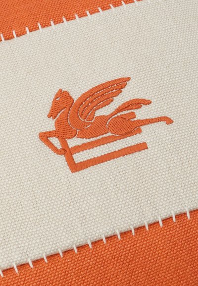 Orange embroidered Pegasus with outstretched wings on white fabric patch, stitched onto an orange textured background.