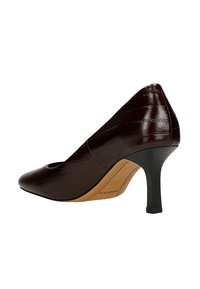 Scarpa con tacco alto in pelle marrone, punta affilata e design a ritaglio, caratterizzata da una finitura lucida e un tacco nero affusolato.