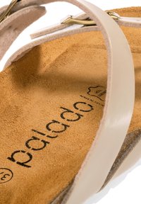 Vita lädersandal med ett guldtonad spänne, med en mocka-brown inlägg och prägling av logotypen på sula, med minimala designelement.