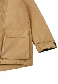 Giacca impermeabile beige con zip frontale, grandi tasche a patta e polsini elasticizzati. Presenta una texture liscia e dettagli riflettenti.